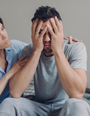 A husband covers his face as his partner comforts him. This could represent the support an affair recovery expert can offer with affair recovery in Boca Raton, FL. 33179 | 33180 | 33311