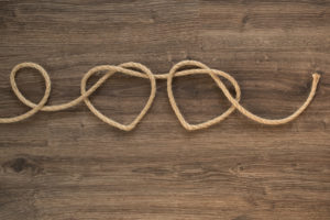 A rope twists into the shape of two hearts on a wooden backdrop. This could represent overcoming infidelity PTSD from cheating. Contact Idit Sharoni to learn how infidelity counseling in Florida can support infidelity recovery.