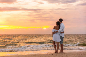 A couple embrace as they watch the sunset over the ocean. Represents how a marriage counseling in miami, fl can help your marriage have better communication and learn you don't need to change your partner. Learn more today!