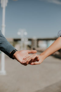 A close up of a couple holding hands as they walk down a boardwalk. This could represent a marriage counselor in Florida. Contact a couples thearpist in Florida for support with couples therapy in Miami, FL.