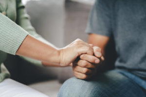 Photo of a couple sitting down holding each other's hands. This photo represents how being vulnerable with your partner can help you when connecting. Learn more with marriage counseling in Florida.