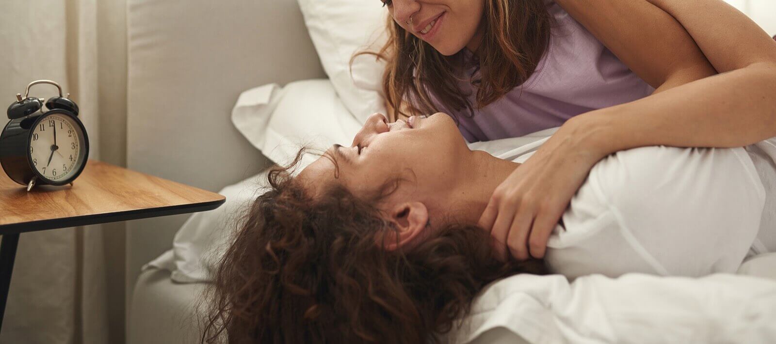 Photo of a couple laying in bed smiling at each other. This photo represents how with strong communication you and your partner can strengthen your relationship. Discover tips from a marriage counselor in Miami, FL here.