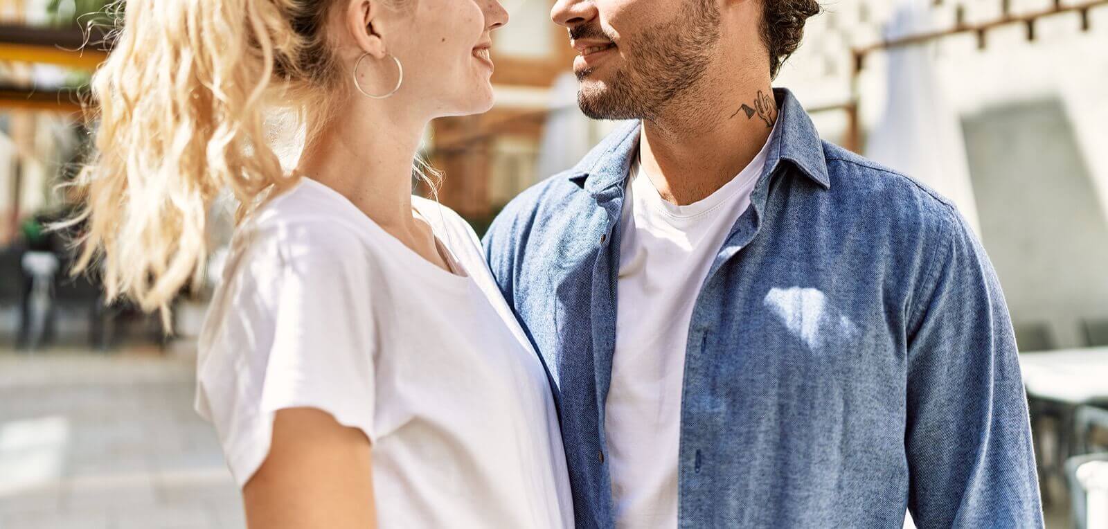 Photo of a couple standing outside and looking at each and smiling. With marriage counseling in Florida, you and your partner can begin to be vulnerable with each other.
