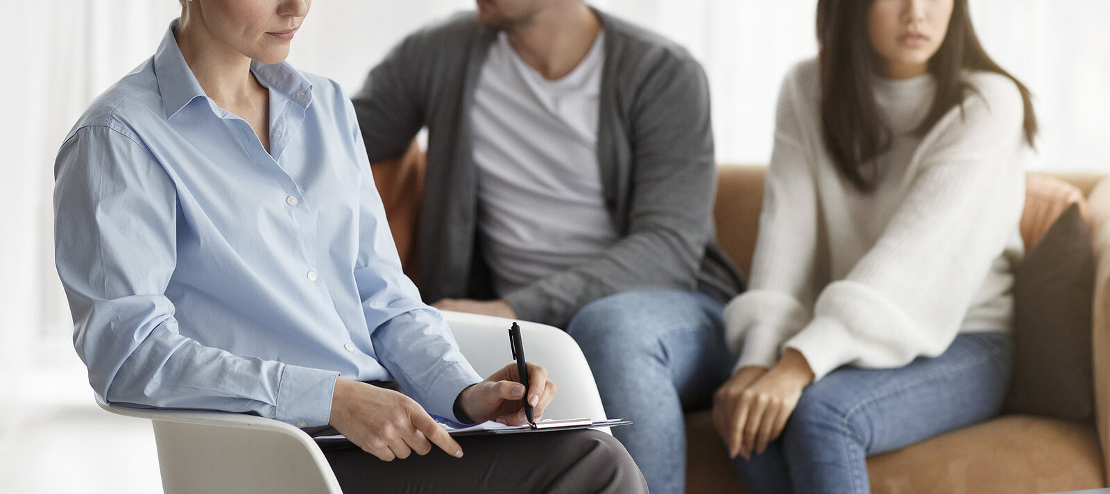 Photo of a couple sitting on a couch talking with a marriage counselor to discuss their relationship. If you and your partner are struggling with trauma in your relationship discover how marriage counseling in Florida can help you and your partner repair your relationship.