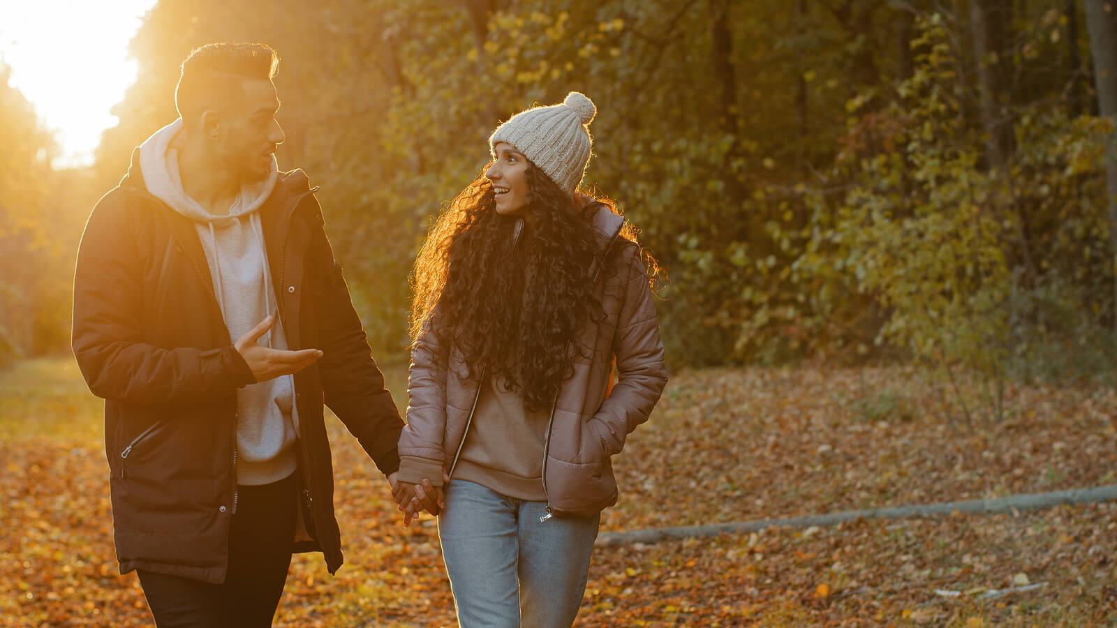 Photo of a couple smiling while holding hands and walking outside during sunset. Are you and your partner struggling with communicating? Gain support from a communication therapist in Florida to reconnect with your partner.
