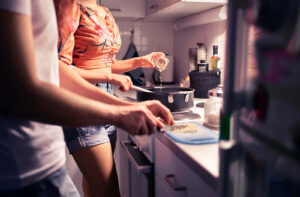 Photo of a couple cooking in a kitchen. Looking for new ways to improve the connection you have with your partner? Learn here how to improve your connections and how marriage counseling in Miami, FL can help.