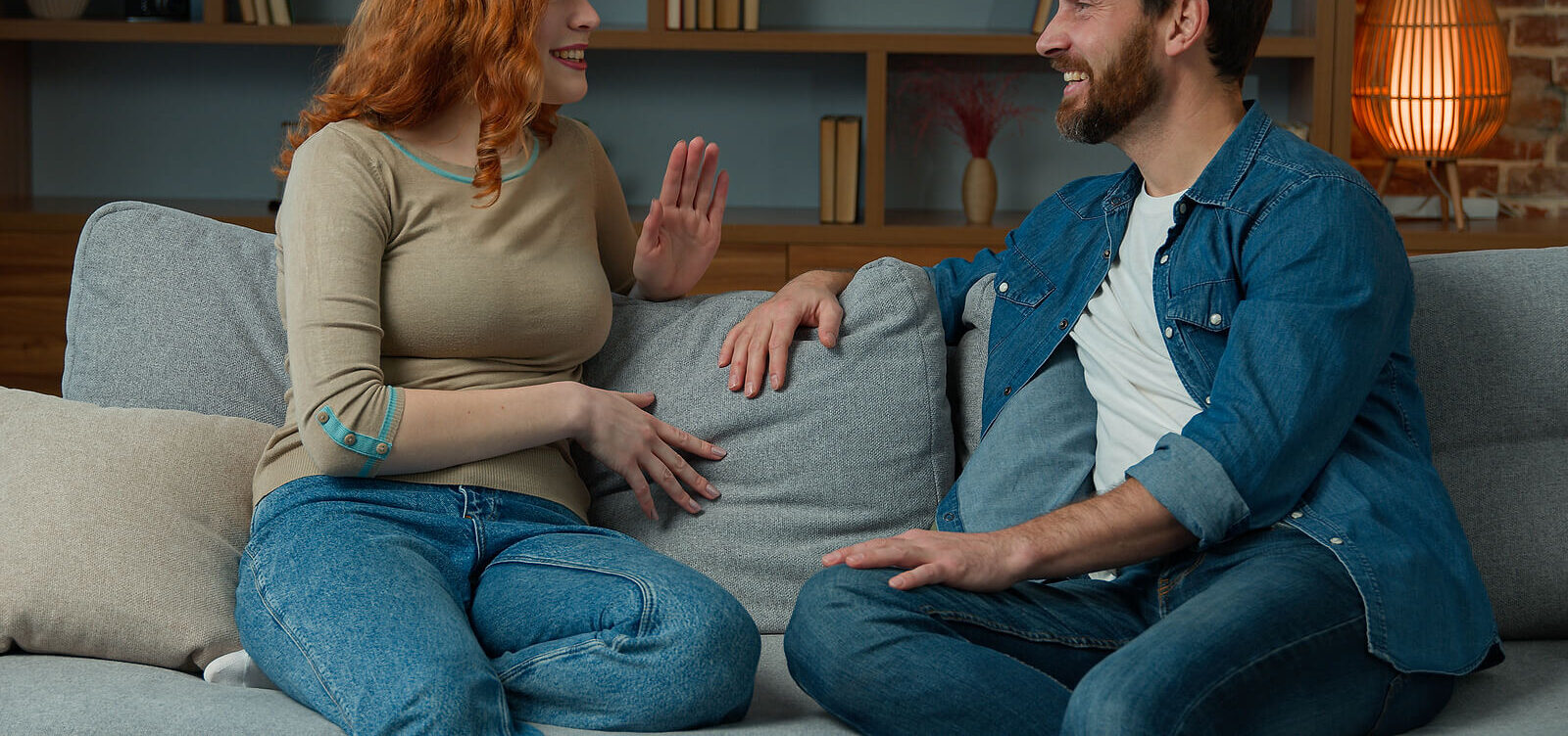 Photo of a couple sitting on a couch facing each other while talking and smiling. Are you looking for ways to communicate effectively with your partner? Learn tips on communicating with a communication therapist in Florida.