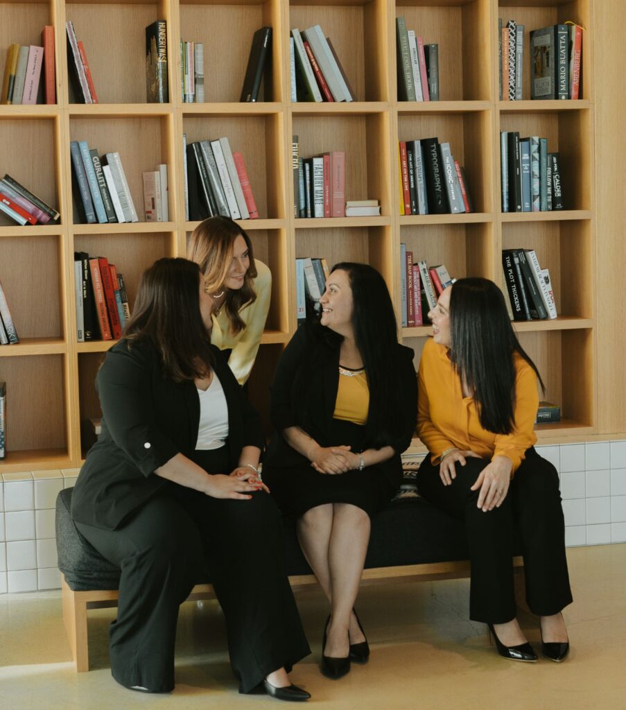 A group of Relationship experts sitting on a bench in a library discussing work | Relationship experts: Idit Sharoni, Yael Haklai-Neagu, Ana De la cruz, Alana Tokayer