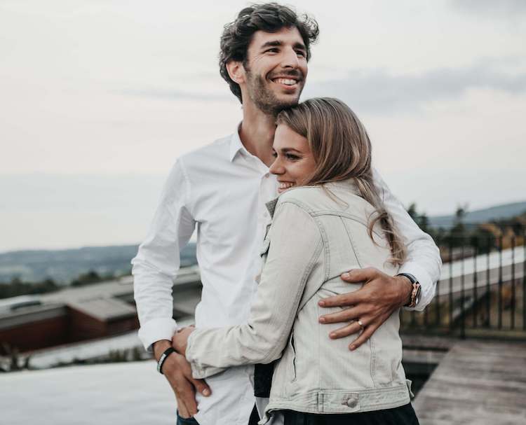 Photo of a couple standing outside smiling and hugging one another. Work to listen to your partner better in couples therapy. A skilled couples therapist in Miami, FL can help you work on your communication styles.