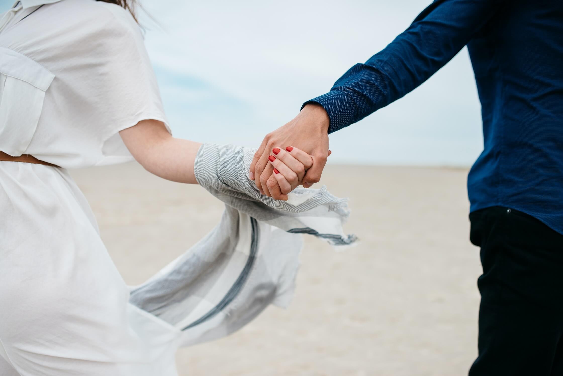 Image of a couple holding hands while standing on a sandy beach. If you struggle with intimacy issues in your relationship, learn how couples therapy in Miami, FL can help you overcome your struggles.