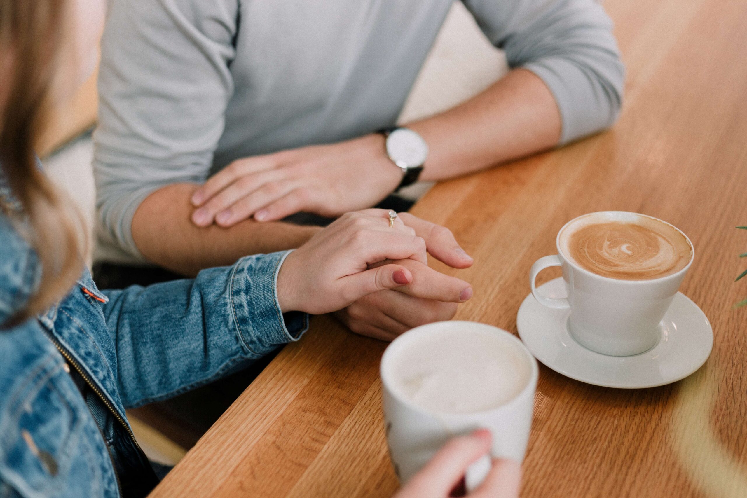 Image of a couple holding hands sitting at a coffee shot with mugs of coffee. Do you and your partner struggle with communication issues? Learn how couples therapy in Miami, FL can help you work through your problems.