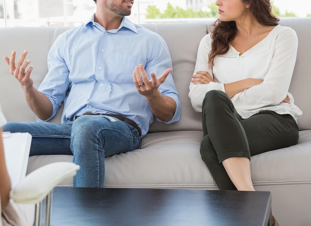 Image of an upset couple sitting on a couch in therapy. Do you have PTSD from past infidelity? Learn from a skilled therapist on how you can best manage your infidelity PTSD with the help of infidelity recovery in Miami, FL.