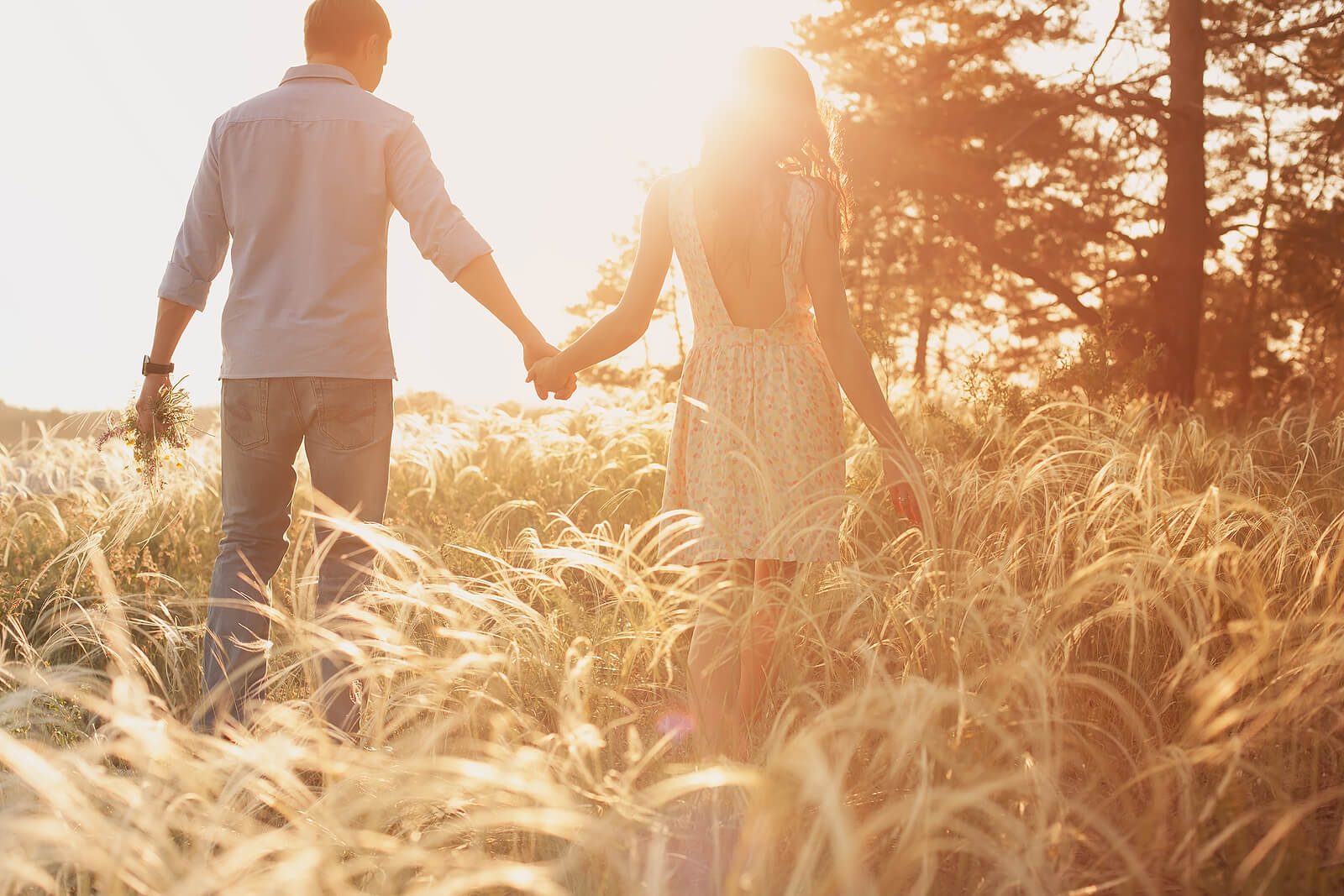 Photo of a couple holding hands and walking in a field during sunset. Struggling to apologize to your partner after an affair? With infidelity recovery in Miami, FL you can begin learning to trust your partner and heal your relationship.