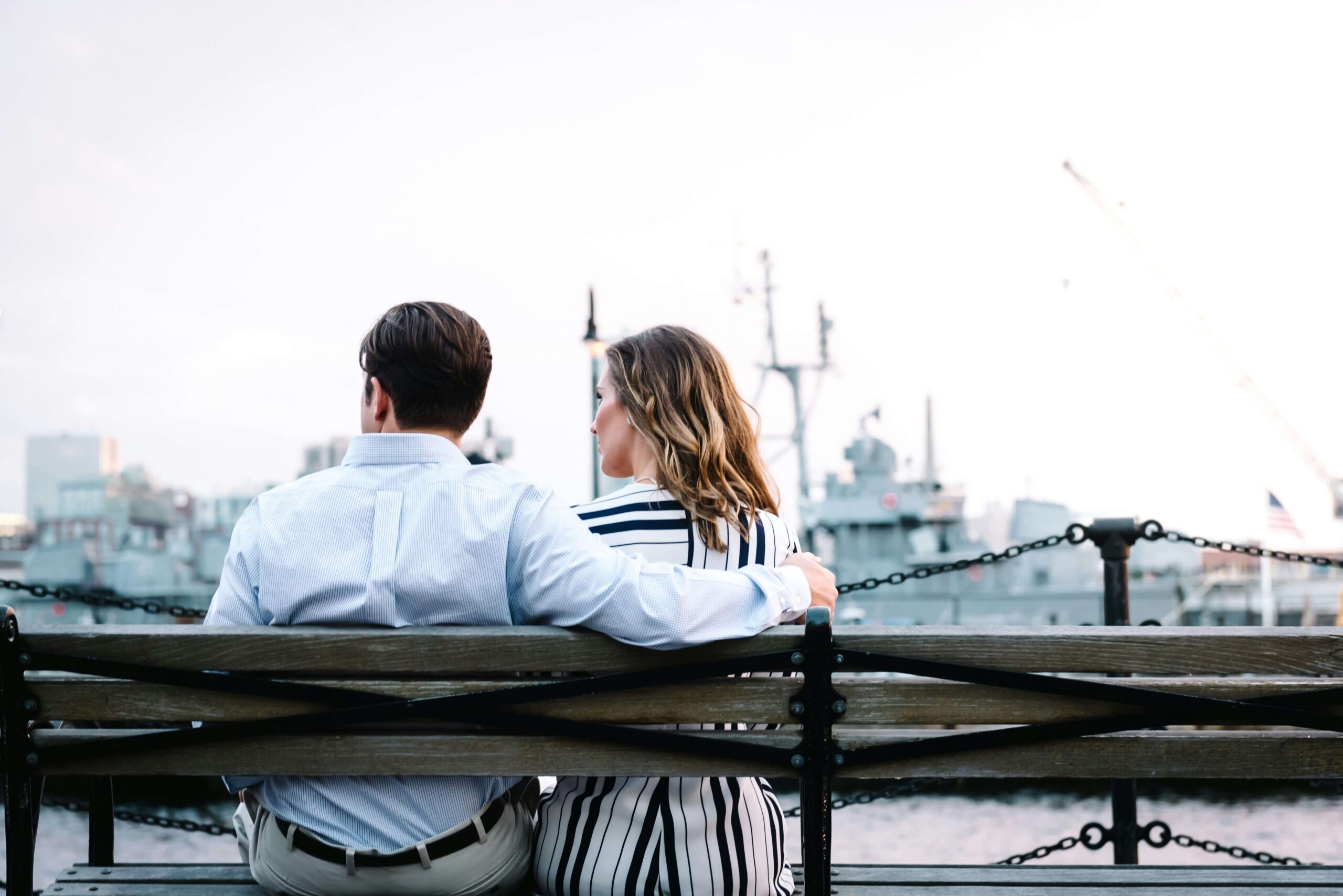 Image of a couple sitting thoughtfully on a bench looking out at water. With the help of couples therapy in Miami, FL, you and your partner can overcome verbal abuse and communication issues in your relationship.