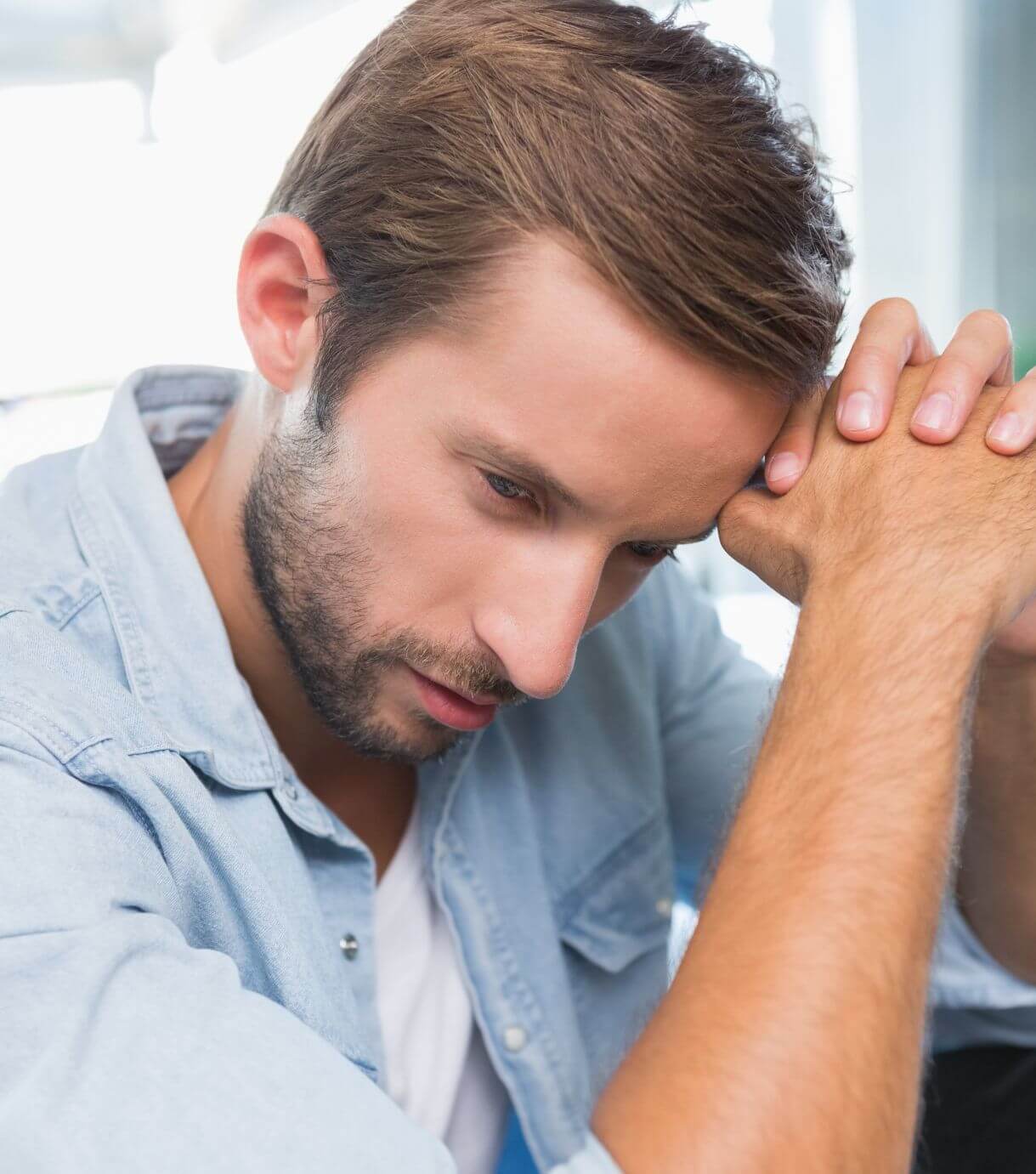 Image of an upset man resting his head against his hands. Discover how to help manage your husband when he feels unappreciated with the help of marriage counseling in Miami, FL.