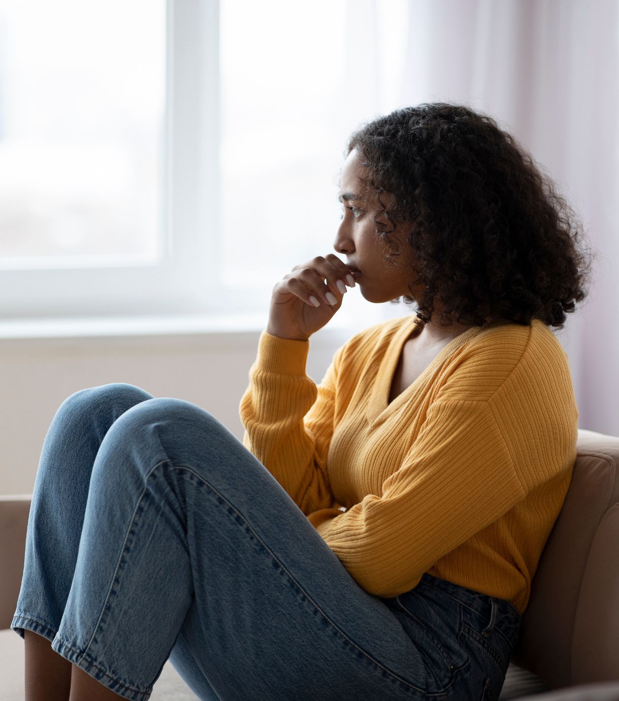 Image of a woman sitting on a couch with her hand to her mouth in thought. Discover how infidelity counseling in Miami, FL can help you and your partner begin healing after an affair. Work with a skilled therapist at Relationship Experts.