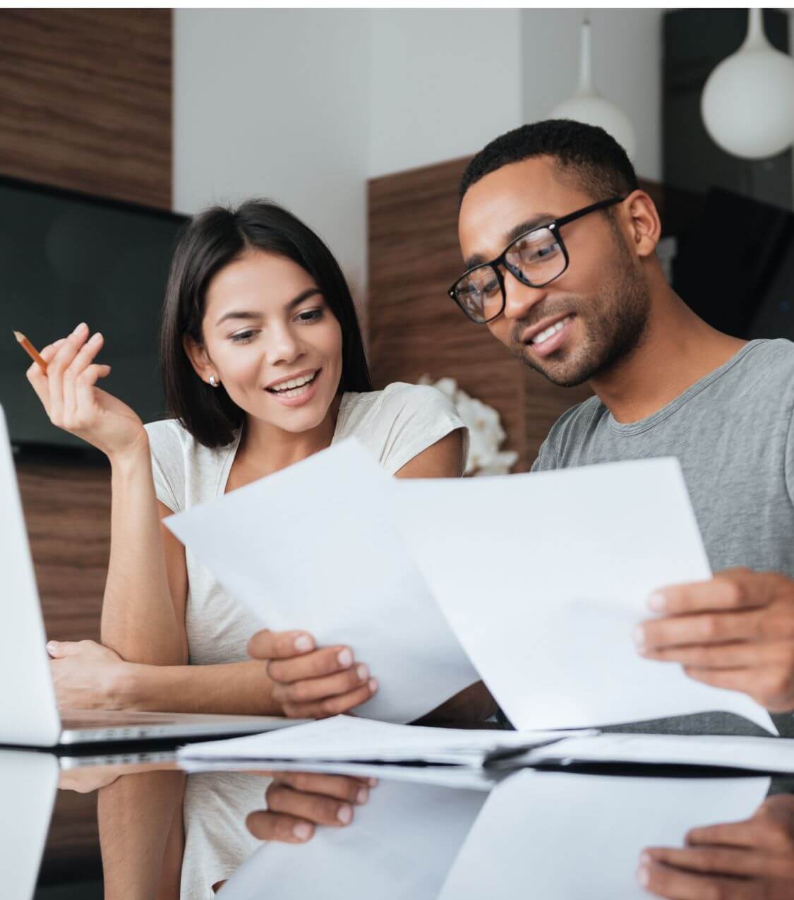 Image of a smiling couple sitting at a table looking at papers. With the help of marriage counseling in Miami, FL you and your partner can work on strengthening your relationship.