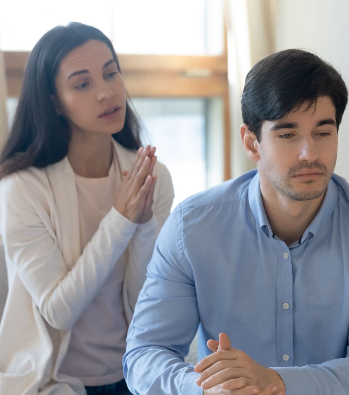 A woman holds her hands together behind a sad man. Learning to forgive after infidelity is challenging but vital to healing after infidelity. Relationship Experts in the USA, Canada, the UK, and globally can help. Schedule a free consultation today.