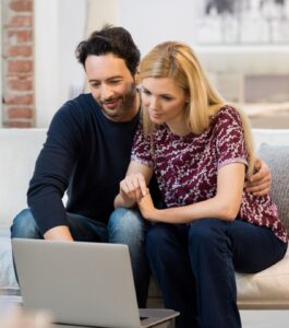 A couple sit in front of a computer. Online couples therapy is effective from the comfort of home and familiar surroundings. Schedule an online couples therapy in Florida, Miami, Orlando, West Palm Beach, Tampa and Weston.