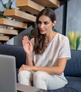 Woman waving during an online video call, representing how counseling sessions over Zoom and virtual couples therapy can feel less awkward for couples with the right guidance. Relationship Experts can help couples in Florida cities like Miami, Orlando, Tampa, West Palm Beach, Naples, Key West, Tallahassee, Port Saint Lucie, and Lakeland while exploring whether virtual therapy is awkward.