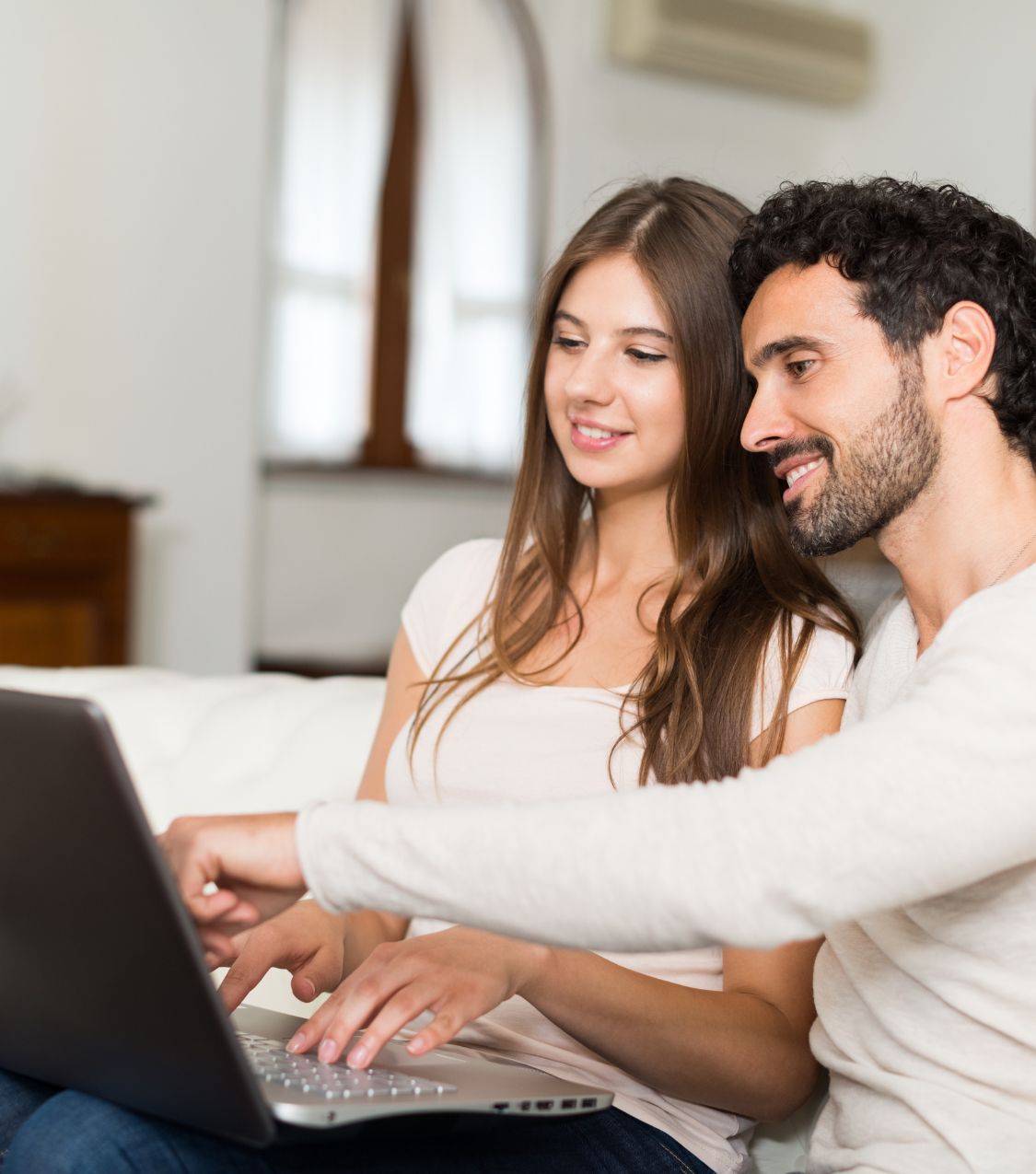 A happy couple sitting together using a laptop for online couples therapy. Learn how to find the best online couples counselor in Fort Lauderdale, Tampa, Orlando, and Sarasota. Start rebuilding your relationship today with expert guidance.
