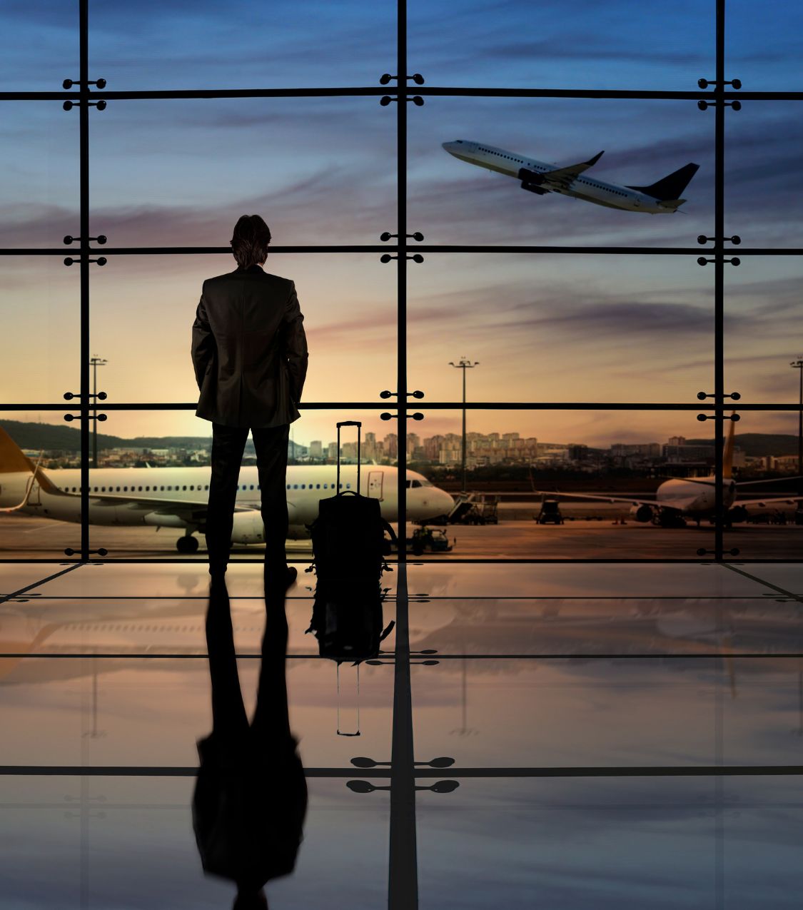 A business traveler stands alone in an airport terminal with a suitcase, watching a plane take off - representing the challenge of maintaining a relationship when one partner travels constantly. Couples therapy long distance, remote couples counseling, and therapy on the go are available for couples in Miami, Aventura, and Ft. Lauderdale. If travel is putting a strain on your relationship, contact Idit Sharoni's Florida couples therapy team today.