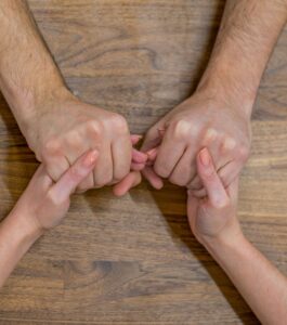 Two people's hands reaching toward each other across a table, fingers gently touching. Reflecting a sign your marriage is still responsive to repair and worth saving, with support from a licensed Florida couples therapist in Miami Beach, Tampa, and Orlando. Schedule your first session to start repairing your relationship.