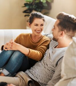 Relaxed couple smiling and talking closely on a couch, at ease with each other after working through conflict. Break the shutdown cycle in your relationship. Help for when your husband gets shut down and understanding why your spouse shuts down during a fight in relationships, with couples therapy across Florida - Sarasota, Delray Beach, and Plantation. Book your consultation today.