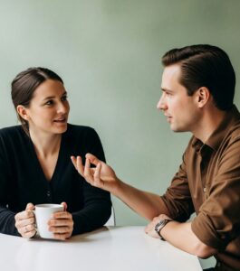 A man and woman sit talking calmly across a table, she listening thoughtfully as he gestures mid-conversation — after a husband had a same-sex affair. Finding a therapist who understands mixed orientation marriages can help you see the signs your marriage is worth saving. Couples in Boynton Beach, Jupiter, and Gainesville can learn how to know if your marriage is worth saving and finally answer "is my marriage worth saving" through licensed therapy. Start your free 45-minute consultation today.