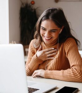 A smiling woman with long brown hair and wired earbuds laughs with her hand on her chest while on a video call at her laptop. EMDR therapy after an affair can help a hurt partner feel lighter again, with online sessions for couples in Miami Beach, Tampa, and Orlando. Schedule a free online consultation to see if EMDR is right for you.
